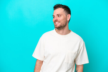 Young Brazilian man isolated on blue background looking side