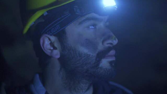 Night miner.
Mandeci looks around with the light of a lantern in the dark. He has black dirt on his face.

