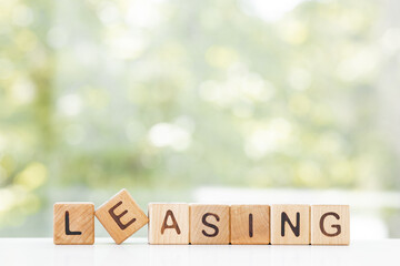 LEASING word is made of wooden blocks lying on the table, concept, green summer background