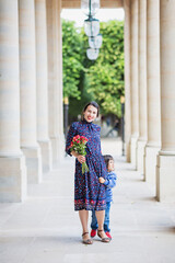 Portrait of elegant woman in a blue dress posing next to a city building with columns at summer