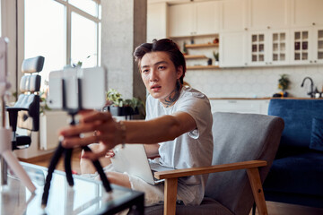 Asian man adjusting the tripod and going to shoot the vlog at home