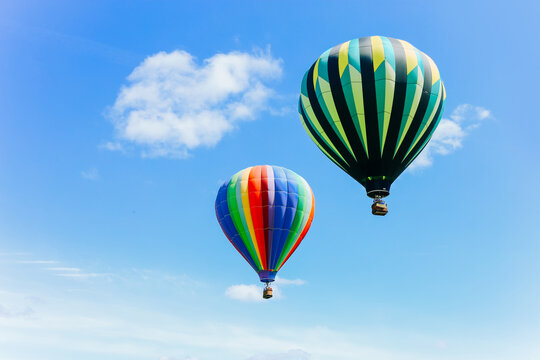 Bright hot air balloons against a blue sky and clouds