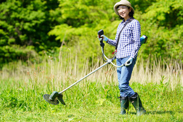 草刈り機で草刈りをする中年女性