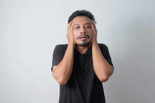 stressed young asian man pulled his face
