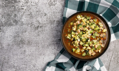 Traditional Russian summer cold soup Okroshka with sausage, vegetables, kvass and dill in bowl on a dark gray background. Top view, flat lay - obrazy, fototapety, plakaty