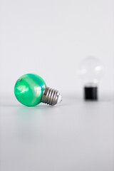 green economy and ideas for the environment, green light bulb idea next to another clear one