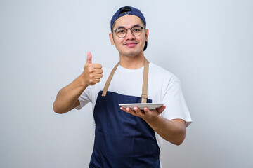 Asian muslim man showing excited expression while holding empty dinner plate