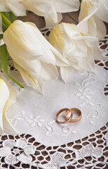 Two wedding rings and white tulips close up.