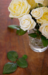 bouquet of blossoming roses in vase on a wooden background