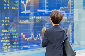 株価を気にする日本人女性の後ろ姿 - obrazy, fototapety, plakaty