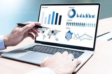 Businessman hand holding pen to display laptop with mockup chart presentation slide show background