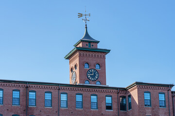 Fototapeta na wymiar The clock tower is a historic cotton mill building in an old industrial park in Nashua, New Hampshire, USA close-up