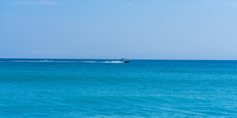 Fototapeta na wymiar Speedboat on the horizon of the turquoise Atlantic Ocean in the early morning in Florida