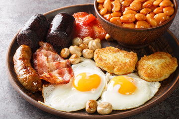 Full Irish breakfast black pudding, egg, beans, sausages, bacon, hash brown, tomato closeup in the...