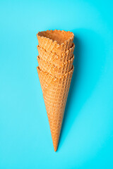 A stack of waffle cones for ice cream on a blue background. Top view, vertical.