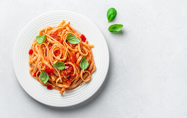 A portion of linguini pasta with tomato sauce and basil on a gray background with a copy space....