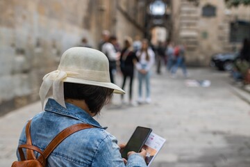 Latin tourist checking her cell phone on the famous gothic bridge Pont del Bisbe in Barcelona (Spain), travel concept.