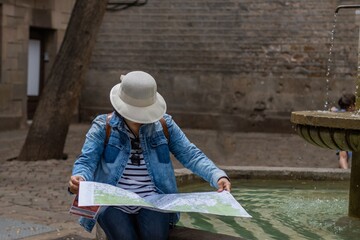 Tourist in Felipe Neri square consulting the map in the gothic quarter of Barcelona (Spain), travel concept.