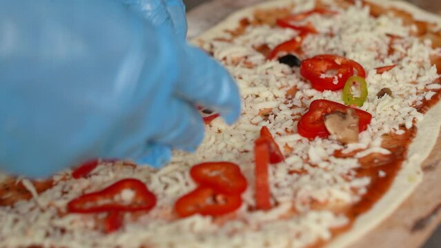 Pizza making, pizza preparation.
The chef, who prepares the pizza, puts the capia peppers.
