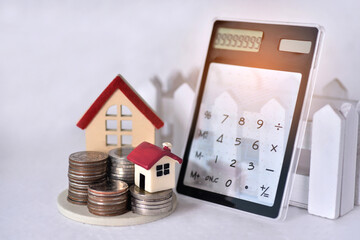 Stacking coins with the big and small red roof house and the calculator lean against the  sunrisefor for calculate the home payment interest of  house loan monthly installment or an equated 