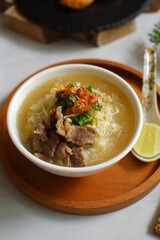 a bowl of beef vegetables clear soup served with rice named soto in Bahasa