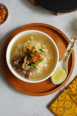 a bowl of beef vegetables clear soup served with rice named soto in Bahasa