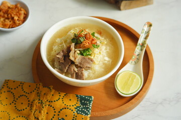 a bowl of beef vegetables clear soup served with rice named soto in Bahasa