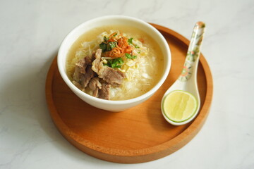 a bowl of beef vegetables clear soup served with rice named soto in Bahasa