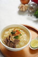 a bowl of beef vegetables clear soup served with rice named soto in Bahasa