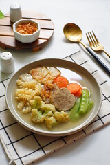a plate of vegetable soup and meat
