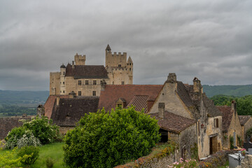 view of the Beynac Castle in the Dordogne Valley under an overcast expressive sky