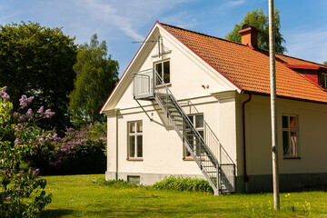 An old cozy white house in vintage style on a sunny day. Ladder and shadow. Beautiful location. 