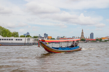 Fototapeta na wymiar A longtail boat, the Chao Phraya River, the Thai royal first class Temple Wat Arun and the Cityscape of Bangkok Thailand Southeast Asia