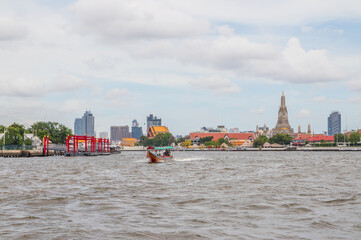 A longtail boat, the Chao Phraya River, the Thai royal first class Temple Wat Arun and the Cityscape of Bangkok Thailand Southeast Asia