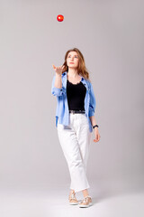 Young beautiful woman in white jeans and a shirt with a red apple. Studio shot.