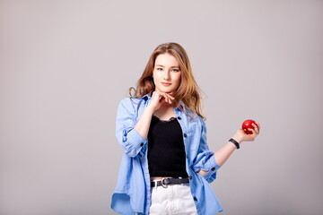 Young beautiful woman in white jeans and a shirt with a red apple. Studio shot.