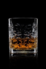 Scotch whiskey in crystal elegant glass on black background.