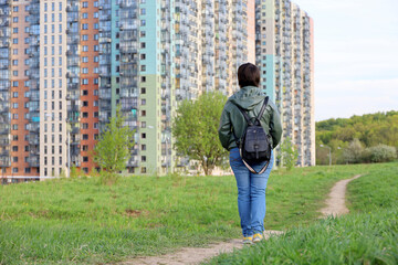 Woman looks at the new houses standing on green hill, ecologically clean district. Building industry and real estate concept