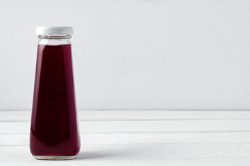 Small glass bottle of fresh juice on white background