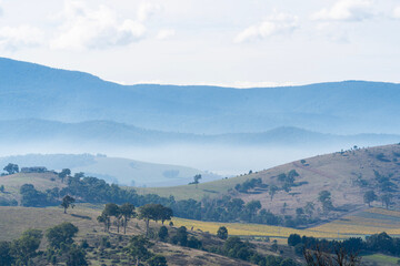 Misty mountain range behind autumnal farmland 