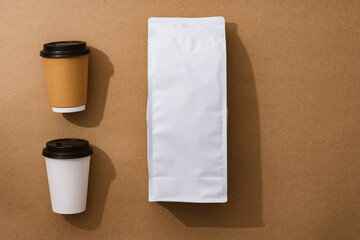 Blank coffee package with copy space and takeout cups on beige background