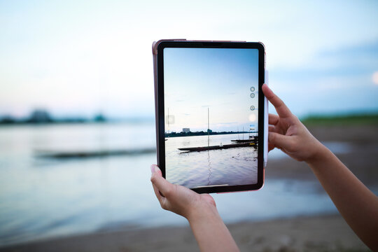 woman using tablet taking photo on beach.