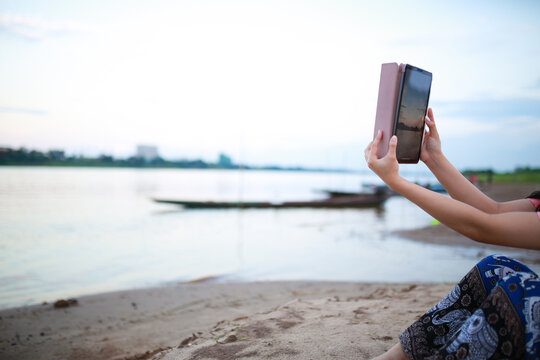 woman using tablet taking photo on beach.