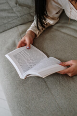 A woman reading a book on the bed - obrazy, fototapety, plakaty