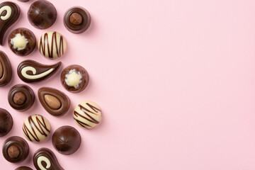 Chocolate pralines assortment on pink background, flat lay, top view with copy space