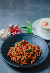 portrait Thai food, beef stir-fried basil rice on texture old cement with fried egg on rice, garlic and dried chilli, basil leaves, famous street food in Thailand, fast food, soft focus