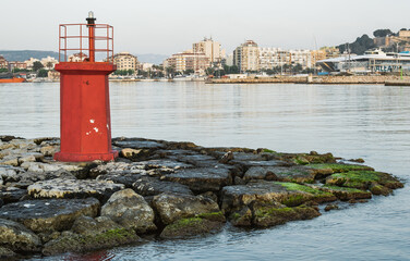Different shots of a red little lighthouse illuminated by the sunlight in Denia, Alicante.