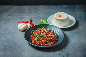 portrait Thai food, beef stir-fried basil rice on texture old cement with fried egg on rice, garlic and dried chilli, basil leaves, famous street food in Thailand, fast food, soft focus