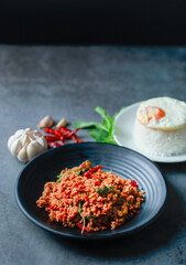 portrait Thai food, beef stir-fried basil rice on texture old cement with fried egg on rice, garlic and dried chilli, basil leaves, famous street food in Thailand, fast food, soft focus