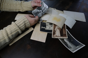 female hands fingering old photos, vintage monochrome photographs 1950, concept of genealogy,...